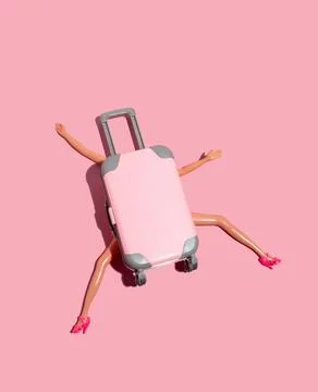 Doll pressed by large suitcase on bright pink background. Funny minimal car.. Stock Photos