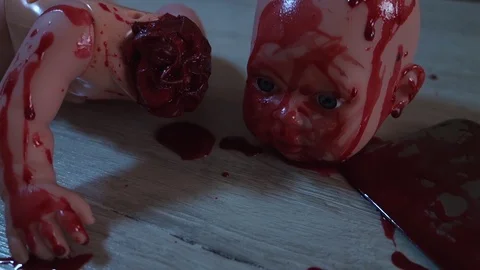 A doll with a severed head in a pool of blood. Bloody knife, halloween concept. Video stock 128258484