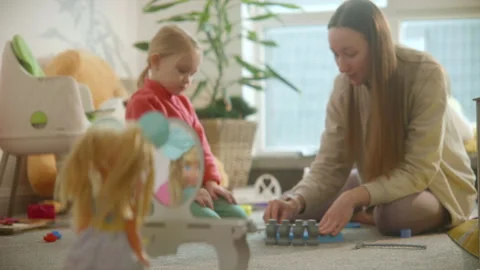 Doll stands at toy table mirror, mom and daughter playing busily on background Stock Footage 244728041