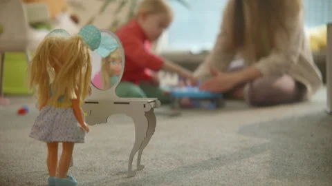Doll stands at toy table mirror, mom and daughter playing busily on background Stock Footage 244933887