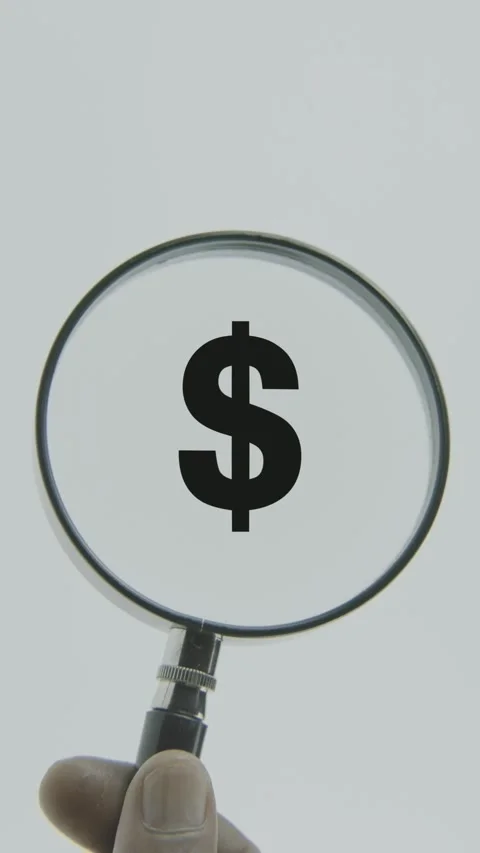 Dollar Sign or Symbol text or word highlighted by a magnifying glass in a ha Stock Footage 303435918