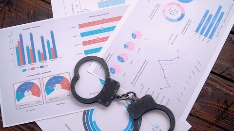 Dollars are scattered on the table with handcuffs and graphs and sales charts Stock Footage 127593054
