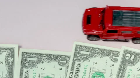 Dollars bills in a row and toy red car is moving fast along the money Vidéo 210218073
