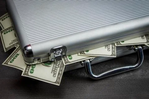 Dollars fall out of a silver suitcase Stock Photos