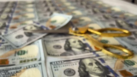 Dollars lie in rows, scissors are lying on top, cutting a bill, out of focus Stock Footage 128410433