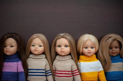 Dolls of different appearance are dressed in sweaters. Stock Photos