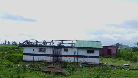Dolly in of abandoned cabin with a missing rooftop in a field in rural Nigeria Stock Footage 320112852