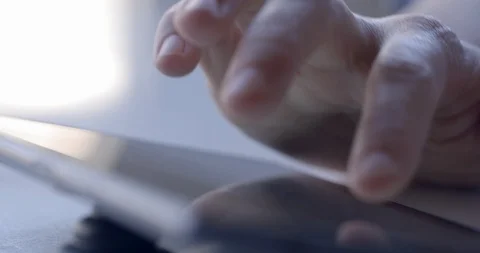 Dolly around woman's fingers using tablet computer at table 4K Stock Footage 86293502