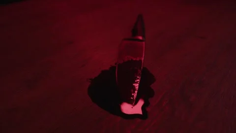 Dolly in of a bloody knife lying in a pool of blood on a horrible crime Stock Footage 278256018