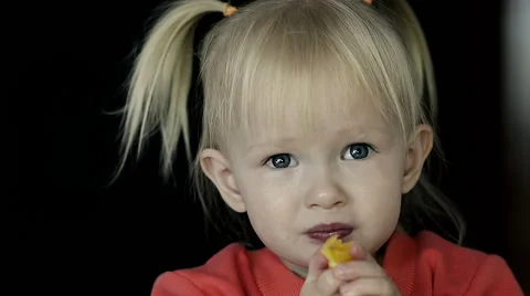 Dolly Close-up of Little blond Girl Eating a slice of Orange Stock Footage