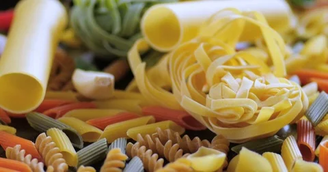 Dolly close up view of different variety of Italian pasta and ingredients Stock Footage 72376382