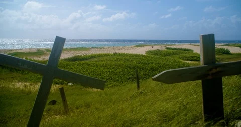 Dolly in fly over two crosses to reveal dunes and ocean. Stock-Footage 98432979