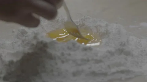 Dolly of fork breaking egg yolk in flour bowl Video stock 149121153