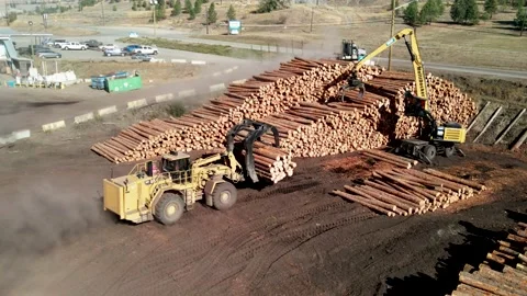 Dolly forward  drone shot of heavy equipment moving log piles at a sawmill Stock Footage 219844071