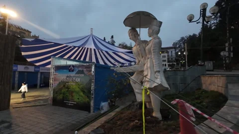 Dolly forward statue in front of blue tent in the evening Stock Footage 295031823