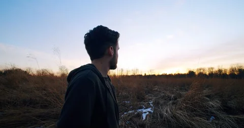 Dolly in on Man Standing In Field During Sunset Stock Footage 122221574