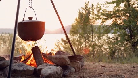DOLLY MOTION: Cooking on fire at sunset. Cooking fish soup on fire. Fishing trip 動画素材 76194562
