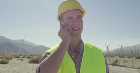 Dolly move around wind farm technician using cellphone 4K Stock Footage 63779478