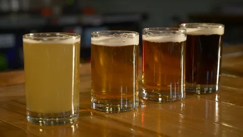 Dolly move into four microbrew beer samples on top of wood bar. Stock Footage 99597649