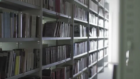 Dolly move of Library shelves with lots of books. Video stock 131104471