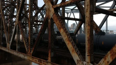 Dolly out shot of train crossing steel bridge in large urban area Stock Footage 100416498