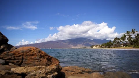 Dolly pull out from volcanic rocks beach in Kihei Maui ocean West Maui Mountains Video stock 119085425