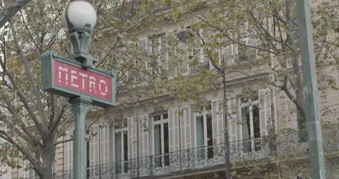 Dolly push in pull back shot of art deco metro sign in Paris with trees Stock Footage 169775644
