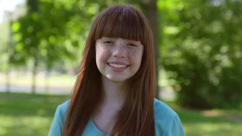 Dolly push shot of smiling redhead teen girl looking at camera standing in Stock Footage 157962646