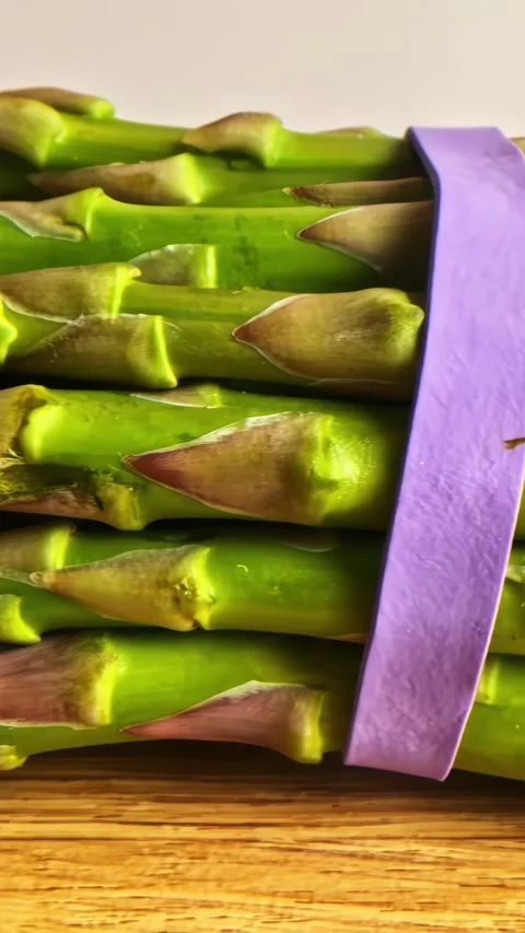 Dolly Right Close Up over Fresh Green Asparagus Tied with Purple Elastic Band Stock Footage 337210518