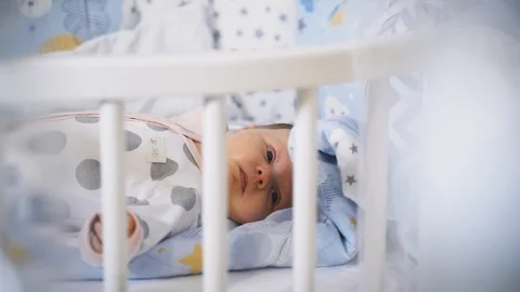 Dolly shoot: a Quiet child lying in the crib. Glare on the lens. Stock Footage 118617825