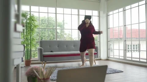Dolly shot Asian plus size female in vr glasses workout exercise online Stock Footage 168170307