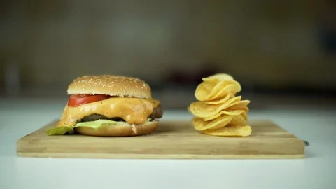 Dolly shot of beef burger cheeseburger next to a stack of potatoes chips. Stock Footage 101965355