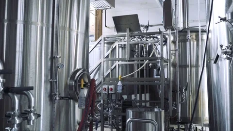Dolly shot of brewer working by storage tanks in brewery Stock Footage