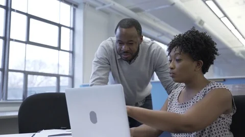 Dolly shot of business colleagues discussing over laptop computer in new office Stock Footage