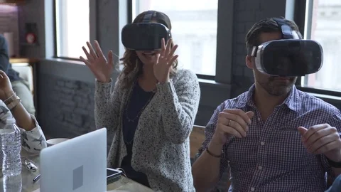 Dolly shot of business people using virtual reality simulator while sitting with Stock Footage