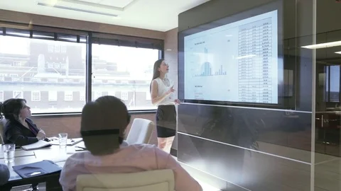 Dolly shot of businesswoman explaining data to colleagues in board room seen Stock Footage