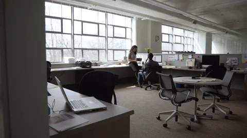 Dolly shot of businesswoman showing tablet computer to colleague in office Stock Footage