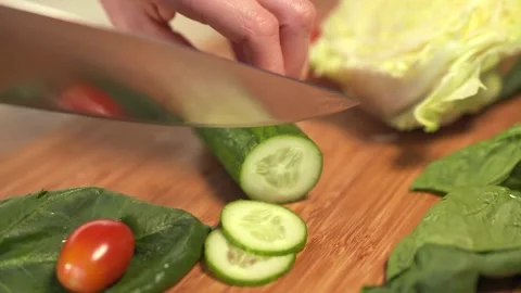 Dolly shot of camera. Woman's hands cutting fresh cucumber on wooden cutting Vidéo 152652126