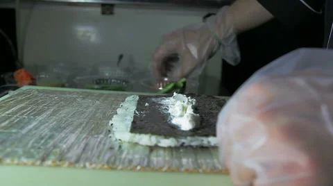 Dolly shot of chef adding salmon and cucumber to sushi rolls 스톡 동영상 41972547