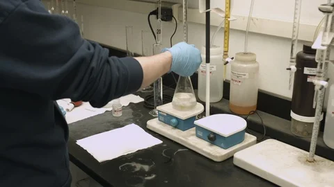 Dolly shot of chemist running a lab experiment with colored liquid in a Stock Footage 116176882