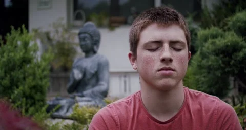 Dolly shot close up of young man meditating and breathing outdoors Stock Footage 130212216