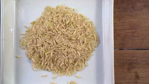 Dolly shot comparison of cooked brown jasmine rice and raw brown rice grains Stock Footage 339479606
