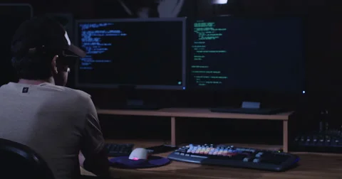 Dolly in shot of Computer hacker sitting in front of screens in a dark room 스톡 동영상 68294762