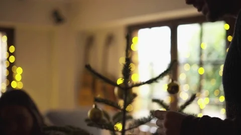 Dolly shot of couple decorating Christmas tree with baubles at home Stock Footage
