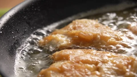 Dolly shot of Crispy Fish Fillets Frying in Bubbling Oil. Stock Footage 258572001