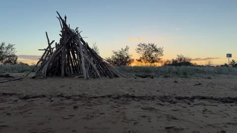 Dolly In Shot of a Driftwood Teepee on the Beach at Sunset Stock Footage 339672929
