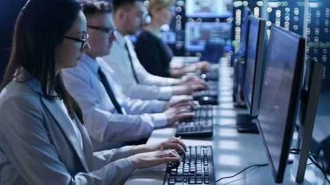 Dolly Shot of Engineers Working on Their Computers in Monitoring Room.  Stock Footage
