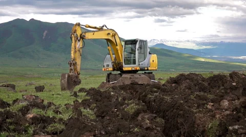 Dolly shot of the excavator digging hole on the mountainous landscape Stock Footage 64694989