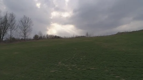 Dolly shot of green empty meadow, with sun rays thru the cloudy sky, 4k Stock Footage 74265212