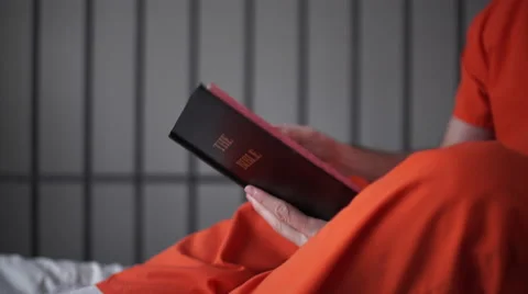 Dolly shot of an inmate reading a bible in prison Stock Footage 59758498
